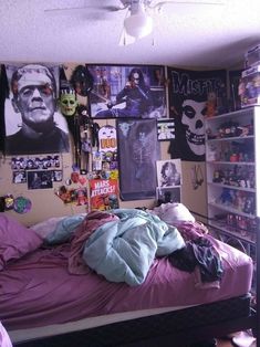 an unmade bed in a room with posters on the wall