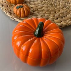 an orange pumpkin sitting on top of a table next to a wicker basket with two small pumpkins in it