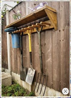 there is a wooden shelf with gardening utensils hanging from it's sides