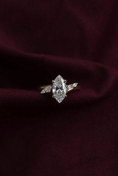 an engagement ring on top of a red cloth with two diamonds in the middle and one diamond