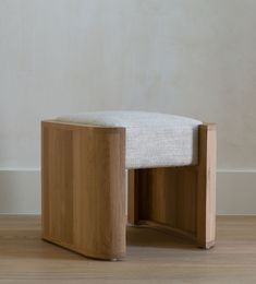 a wooden bench sitting on top of a hard wood floor next to a white wall