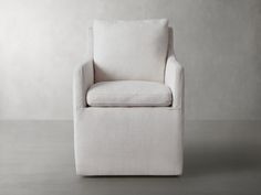 a white chair sitting on top of a floor next to a gray wall with no one in it