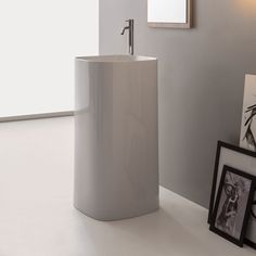 a white sink in a bathroom next to a framed photograph and pictures on the wall