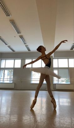 a ballerina in a dance studio with her arms stretched out and one leg bent forward