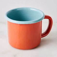 an orange and blue mug sitting on top of a white counter next to a wall