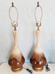 two brown and white vases sitting next to each other on top of a table