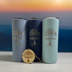 three different colored tumblers sitting next to each other on a white table with a sunset in the background