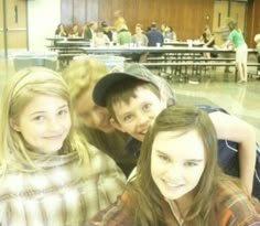 three young people posing for a photo in front of a class room full of students