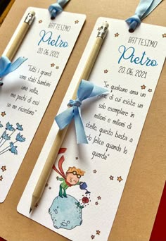 two bookmarks with blue ribbon tied to them sitting on a table next to a fork and knife