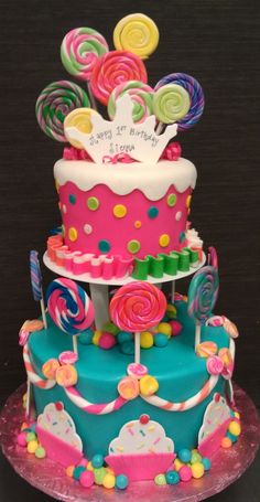 a three tiered cake decorated with candy and lollipops