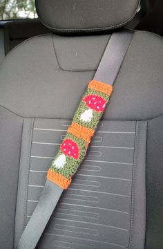 the seat belt is decorated with crochet and mushrooms