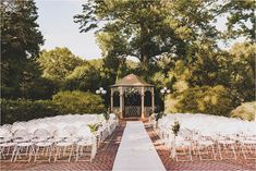 an outdoor wedding venue with white chairs and a gazebo set up for the ceremony