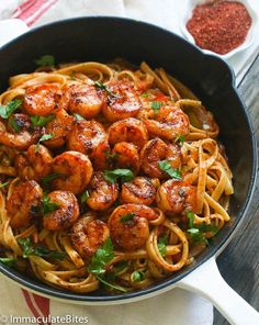 a pan filled with shrimp and pasta on top of a table