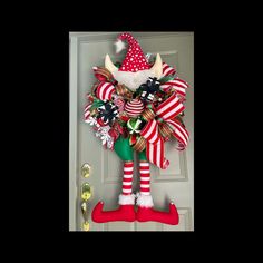 a door hanger decorated with red and white striped stockings, santa's hat and boots