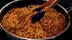 spaghetti being cooked in a pan with chopsticks sticking out of the top one