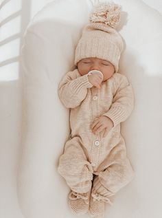 a baby is laying down wearing a knitted outfit