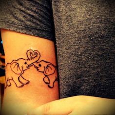 a woman's arm with an elephant and heart tattoo on the side of her wrist