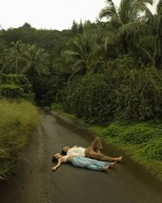 a person laying on the side of a road with palm trees in the back ground