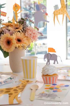 a table topped with cupcakes and flowers next to a vase filled with flowers