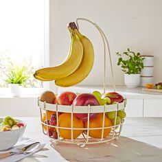 a basket filled with fruit sitting on top of a counter next to a bowl of fruit