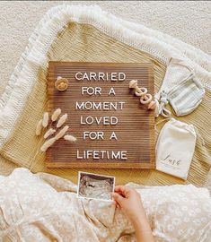 a person laying on top of a bed next to a sign that says carried for a moment loved for a life time