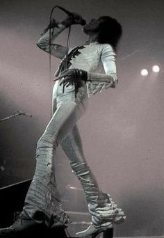 a woman in white outfit standing on stage with microphone