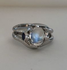 The Crystal Ball Ring is a very unique design, crafted by Heirloom Pavé in 18K white gold, featuring a Cabochon Moonstone. And two perfectly blue round brilliant Sapphires. The Moonstone is a oval shape Cabochon with a beautiful iridescent that so mystical and other worldly looking. The two, bezel-set Sapphires are a total carat weight of .35ct are a beautiful accent to the center. In the high polished white gold it is a true statement piece. Size 7 (Sizable upon request) Every Antique piece of Crystal Ball Ring, Funky Rings, Other Worldly, Ring Crystal, Custom Pendants, February Birth Stone, Multi Stone Ring, White Gold Ring, Multi Stone