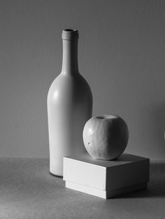 two white vases sitting on top of a table next to an apple and a bottle