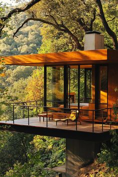 a house in the woods surrounded by trees and greenery is built on top of a wooden platform