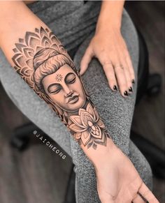 a woman's arm with a buddha tattoo on it