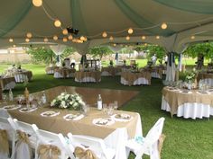 tables and chairs set up under a tent for an outdoor wedding reception at the park