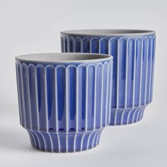 two blue vases sitting side by side on a white surface