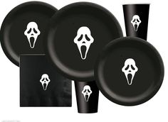 a set of black dinnerware with white ghost faces on the front and back plates