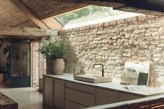 a kitchen with a brick wall and white counter top next to a planter filled with potted plants