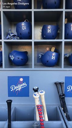 some baseball bats and helmets are in a dugout area with the dodgers logo on it