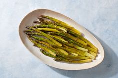 asparagus spears on a white plate against a light blue background, ready to be eaten