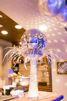 a disco ball sitting on top of a table in front of a mirror and balloons