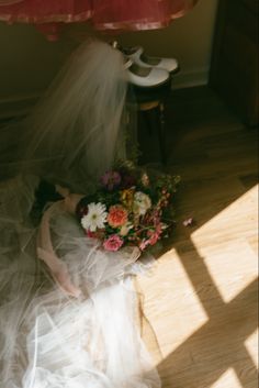 the bride is laying on the floor with her wedding dress blowing in the wind and holding a bouquet of flowers