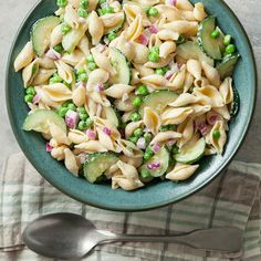 a bowl filled with pasta, peas and cucumbers on top of a table