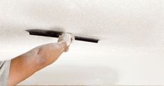 a man is painting the ceiling with white paint