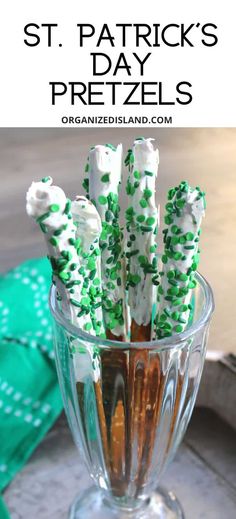 there are green and white candy sticks in the glass cup on the table with napkins