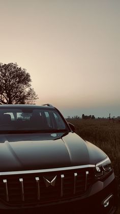 a black car parked in front of a tree