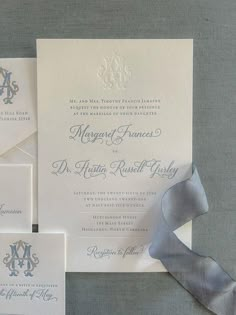 the wedding stationery is set up with silver ribbon and monogrammed envelopes