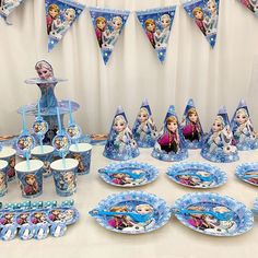 the table is set up with plates, cups and napkins for frozen princess party