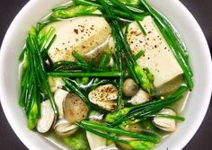 a white bowl filled with green vegetables and tofu