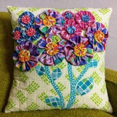 a pillow with flowers on it sitting on a green chair in front of a wall