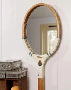 there is a mirror on the wall next to an old box and a wooden racket