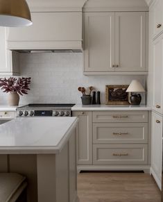 a kitchen with white cabinets and wood floors