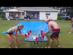 two people standing in front of a table with drinks on it and one person wearing a bathing suit