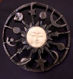 a metal sun and moon decoration on a black surface